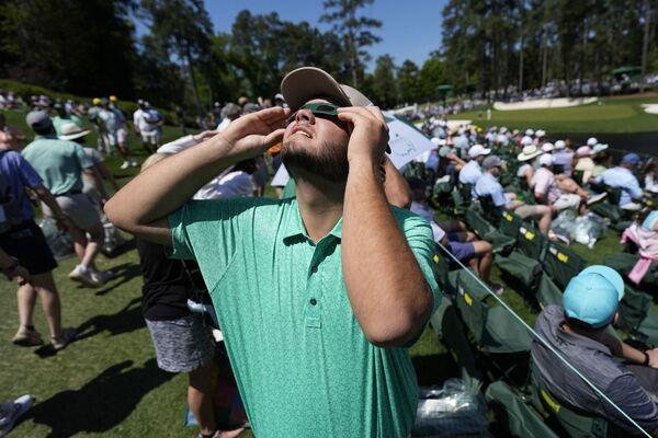 A patron looks up at the sun during an solar eclipse during a practice round in preparation for the Masters golf tournament at Augusta Natio<em></em>nal Golf Club Monday, April 8, 2024, in Augusta, Ga. (AP Photo/Ashley Landis)